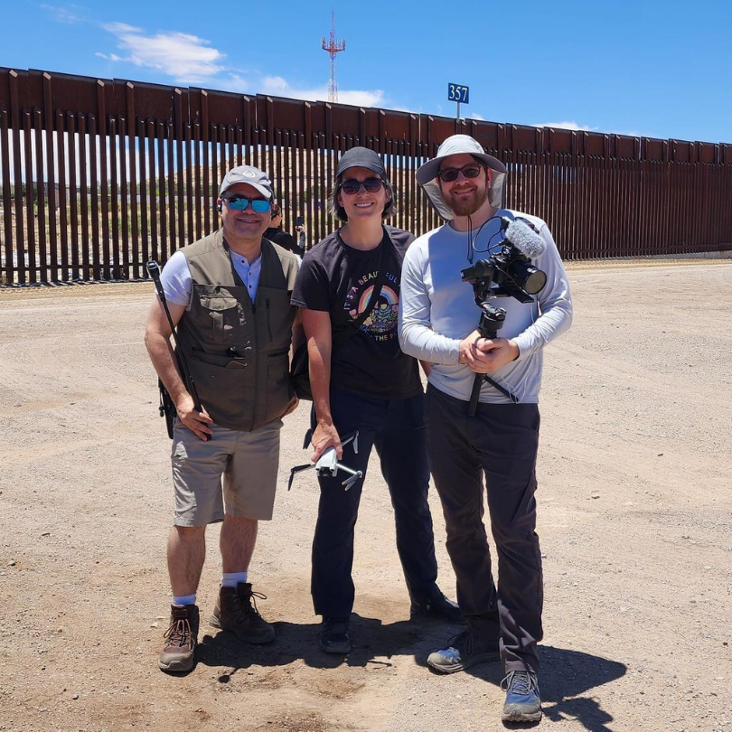 Three men stand with camera equipment